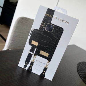 Idel of sweden, iPhone 12 - Ett skal för iPhone 12 med tillhörande band+väska. 1 vecka gammalt, helt och fräscht. Min telefon gick sönder därav säljer jag det.   Ordinarie pris 799kr säljer för 400kr.