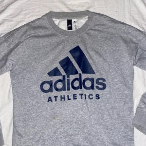 Adidas hoodie  - Grå adidas hoodie med blå text framtill. 