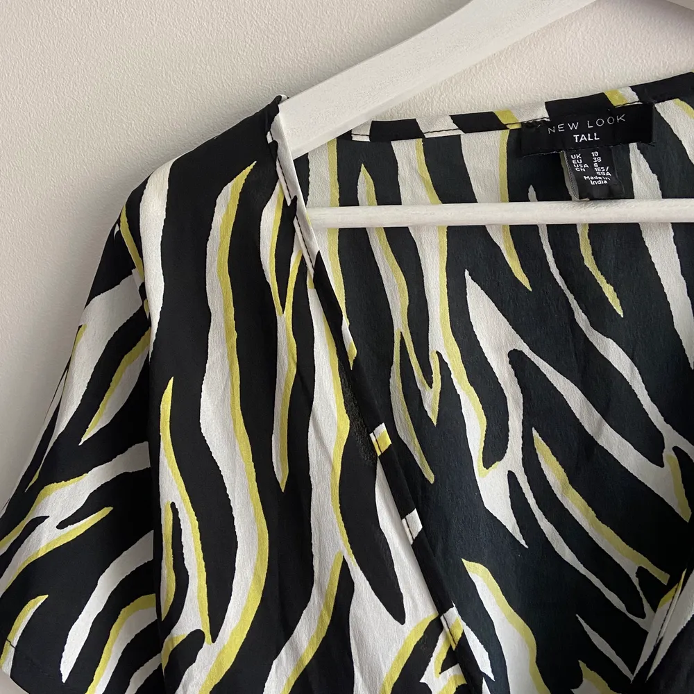 Gul svart och vit zebramönstrad omlottklänning som man knyter beroende på hur man vill ha den! Aldrig använd. Från newlook, säljes pga passar ej:(. Klänningar.