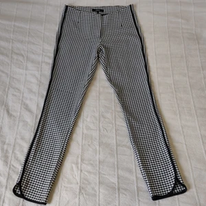 Svartvita mönstrade byxor, strl 36 - Mjuka, stretchiga byxor i hundtandsliknande mönster och med snygga detaljer. Svartvita och lite kortare i modellen. Använda ett par gånger och är som nya. 63% polyester 31% viskos och 6% elastan. Storlek 36.