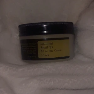 COSRX Advanced Snail 92 All in One Cream - Säljer en burk med COSRX Advanced Snail 92 All in One Cream. Denna kräm är känd för sin återfuktande och reparerande effekt tack vare snigelextrakt. Perfekt för att ge huden en mjuk och smidig känsla. Öppnad och testad men är helt full av produkt. Om ni vill se hur den ser ut inuti så skriv 🩷original pris 250