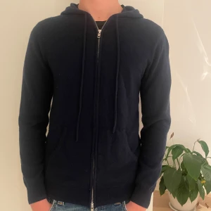 Mörkblå hoodie från John Henric - Säljer en stilren mörkblå hoodie från John Henric i mjuk kashmir. Tröjan är sparsamt använd och finns inga defekter. Säljer då den är för liten.