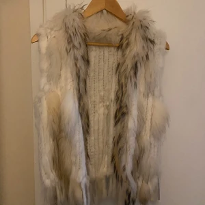 Vit pälsväst - Säljer en fluffig och stilren vit pälsväst med inslag av beige. Västen har en mjuk och lyxig känsla, perfekt för att hålla värmen under kyliga dagar. Den är utan ärmar och har en naturlig look som passar till många olika outfits. Passar xs-l 