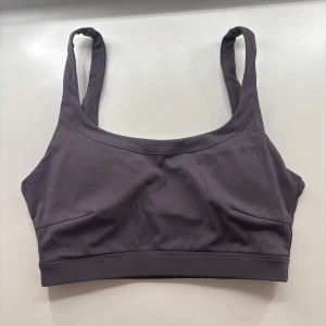 Lila sporttopp från ICANIWILL - Snygg lila sporttopp från ICANIWILL med breda axelband och rundad hals. Perfekt för träning med sin bekväma passform och stilrena design. Toppen har en diskret logga på bröstet.