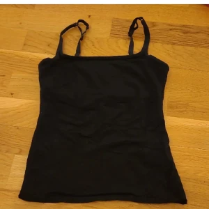 Svart linnetopp från Zoul - Snygg svart linnetopp från Zoul i storlek XS. Perfekt för varma dagar eller som lager under andra plagg. Den har smala, justerbara axelband och en enkel design som gör den lätt att matcha med olika outfits.
