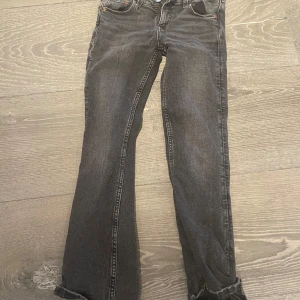 Svarta jeans från Gina Tricot - Snygga svarta jeans från Gina Tricot i barnstorlek 140. De har en klassisk femficksdesign och knappstängning. Perfekta för en stilren look.
