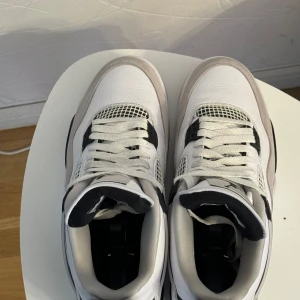 Nike Air Jordan 4 Retro - Säljer ett par stilrena Nike Air Jordan 4 Retro i vitt, svart och grått. Skorna har en klassisk design med snörning och detaljer i syntetmaterial. Perfekta för sneaker-entusiaster! Använt cirka 2gånger samt som nya (äkta)
