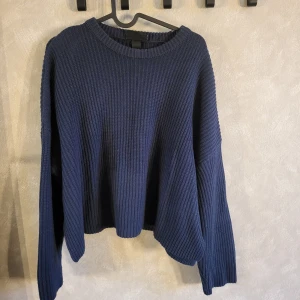 Mörkblå stickad tröja från Monki - Säljer en snygg mörkblå stickad tröja från Monki. Tröjan har en avslappnad passform med långa ärmar och rund halsringning. Perfekt för kyligare dagar!