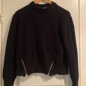 Svart stickad tröja med dragkedjor - Säljer en svart stickad tröja från Ginatricot med  dragkedjor framtill. Tröjan har en ribbad design och långa ärmar.