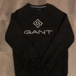 Svart tröja från GANT - En svart tröja från GANT med deras logga på framsidan. Tröjan har långa ärmar och en rund halsringning. Knappt änvänd.
