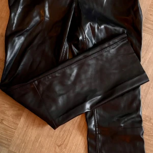 Svarta skinnbyxor från Carin Wester - Snygga svarta skinnbyxor från Carin Wester i storlek 40. Byxorna har en stilren design med raka ben och diskreta bakfickor. Perfekta för en trendig look.
