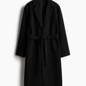 Svart kappa med bälte - Elegant svart kappa med bälte och långa ärmar. Perfekt för kyligare dagar med sin stilrena design och klassiska snitt. Använd en gång 