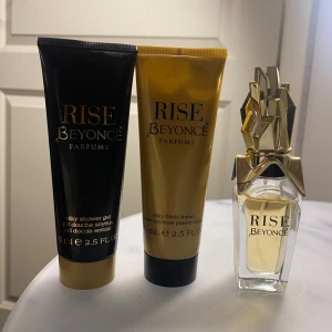 Rise Beyoncé Parfymset - Exklusivt parfymset från Beyoncé med doften Rise. Innehåller en elegant parfymflaska med en unik guldfärgad kork, samt en silkeslen duschgel och body lotion i matchande design. Perfekt för att känna sig lyxig.