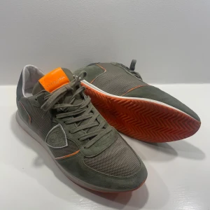 Gröna Philip Model - Snygga gröna Philip Model med orange detaljer. Skorna har en kombination av mocka och syntetmaterial. Skorna är i riktigt fint skick! De är 44 men tycker de är lite mindre då jag oftast har 43. De är perfekta för vintern.