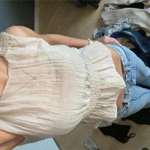 Beige ärmlös blus - Pris kan diskuteras! Säljer en söt beige ärmlös blus med smockdetaljer vid axlar och midja. Blusen har en luftig och lätt design, perfekt för varma dagar. Den är tillverkad i ett tunt och skönt material som ger en avslappnad look. Säljer pga används inte. Lite genomskinligt material💕