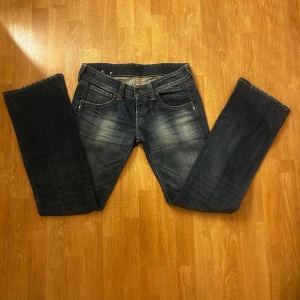 Blå jeans från Replay - Säljer ett par snygga blå jeans från Replay med klassisk femficksdesign och en cool läderdetalj med blommor på baksidan. Jeansen har en lätt tvättad look och raka ben. Aldrig använda då dom var för stora. Pris kan diskuteras 💗