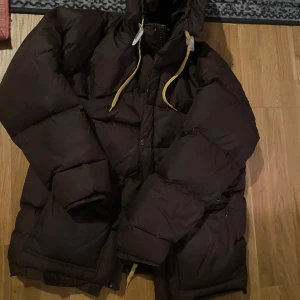 Brun dunjacka med huva - Fjällräven jacka haft den typ 3 år, märks tilvisso men inget som stör , storlek m