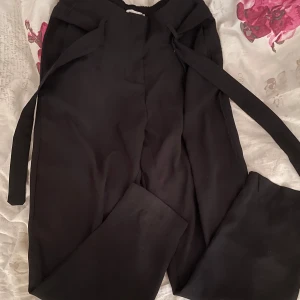 Svarta byxor med knytband - Säljer ett par svarta byxor med hög midja och knytband i midjan. De är superbekväma och har en loose passform.