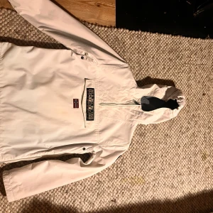 Vit jacka från Napapijri - PRIS KAN DISKUTERAS✨✨‼️.                      Säljer en stilren vit jacka från Napapijri med en broderad logotyp och norsk flagga på framsidan. Jackan har en praktisk dragkedja och huva, perfekt för kyliga dagar. Den är långärmad och har tejpade sömmar för extra skydd mot väder och vind.HELT OANVÄND!                                 Skriv vid intresse. PRIS KAN DISKUTERAS✨✨‼️
