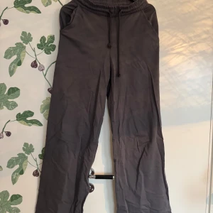 Grå mjukisbyxor från NY Trend - Säljer ett par grå mjukisbyxor från NY Trend i storlek XS. Byxorna har en elastisk midja med snörning för justerbar passform och vida ben för en avslappnad stil.