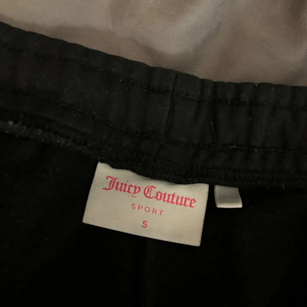Snygga svarta mjukisbyxor från Juicy Couture med stort tryck längs benet. Perfekta för en avslappnad stil med elastisk midja och dragsko för bästa passform, fickor på sidorna. Lite använda storlek small . Farkut & Housut.