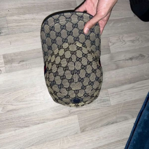 Gucci keps  - Snygg beige keps från Gucci med det ikoniska monogrammönstret. Kepsen har en justerbar rem baktill och en klassisk skärm. Perfekt för att ge din outfit en lyxig touch. Knappt använd 