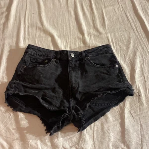 Svarta jeansshorts från H&M Divided - Snygga svarta jeansshorts från H&M Divided med fransiga kanter och klassisk femficksdesign. Perfekta för en avslappnad stil under varma dagar. 🖤