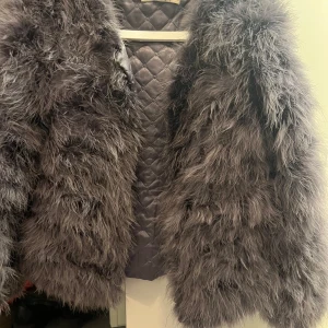 Grå pälsjacka från DM - Säljer en fluffig och trendig grå pälsjacka från DM. Jackan är i äkta struts. 