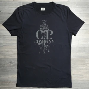 Mörkblå Cp Company T-Shirt  - Säljer nu denna riktigt snygga Cp Company T-shirten. Tröjan är i väldigt fint skick. Storlek M. Nypris ca 1000kr, mitt pris endast 499kr. Hör av dig om du undrar något eller vill ha fler bilder! Pris är diskuterbart vid snabb affär🤝