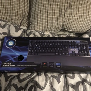 Gamingtangentbord från Qpad - Säljer ett gamingtangentbord från Qpad, modell MK-50. Det har mekaniska brytare och en avtagbar handledsstöd. Perfekt för att förbättra din spelupplevelse med volymkontroll och belysta tangenter. Kommer i originalförpackning. Pris kan diskuteras, öppnad bara för att testa annars helt oanvänd. Skicket är helt nytt.