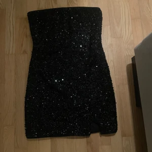 Svart paljettklänning - Snygg glittrig bandeau klänning som är perfekt ny till nyår, säljer då den är lite för stor för mig 