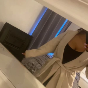 Beige kappa - Köpt på hm. Går att vika vid bröstet . Har även knappar och är precis över knät i längd.