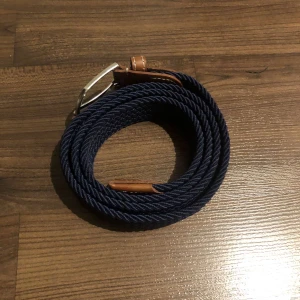 Flera flätade bälten med metallspänne - Säljer ett gäng snygga flätade bälten i olika färger. De har ett stilrent metallspänne och detaljer i brunt läder. Perfekt för att ge din outfit en cool touch. Finns i färgerna blå, svart, grön, vit, beige och svartvit randig.
