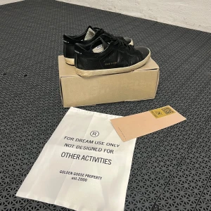 Svarta sneakers från Golden Goose - Säljer ett par Snygga svarta sneakers från Golden Goose i storleken 40 passar 41-42. 8/10 i skick, har en liten defekt på vänster sula. Perfekta för en stilren look. Pris kan diskuteras vid snabb affär 