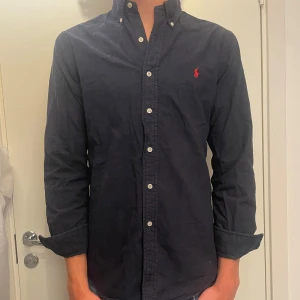 Mörkblå Ralph Lauren skjorta  - Säljer nu min mörkblåa Ralph lauren skjorta då den inte har använts något. Skicket är riktigt fint och skjortan har inga defekter. Skriv för minsta lilla fråga eller fler bilder.