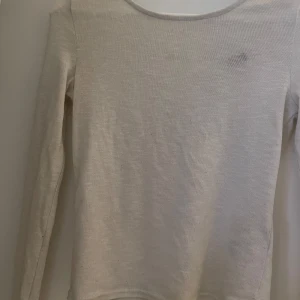 Vit tunn långärmad tröja - Säljer en vit tunn tröja med lång ärm och snörning i ryggen. Lite genomskinlig (kolla sista bilden)
