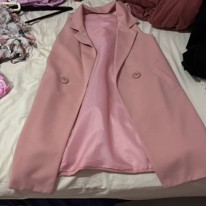 Rosa kavaj från SIJIFENG - Snygg rosa kavaj från SIJIFENG med en stilren design. Kavajen har en klassisk krage och två knappar framtill. Perfekt för att ge en färgklick till din outfit.