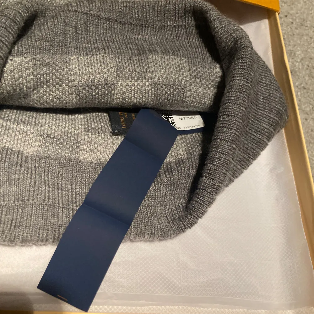 Snygg grå mössa från Louis Vuitton med klassiskt rutmönster. Mössan har en ribbad kant och en diskret logotypplatta framtill. Perfekt för att hålla stilen i kallare väder.. Asusteet.