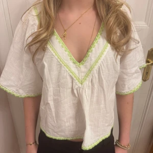 Vit blus med gröna detaljer - Snygg vit blus med gröna broderade detaljer längs halsringningen och ärmsluten. Använd max en gång 