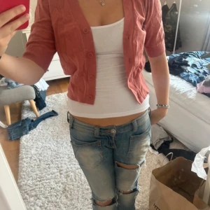 Rosa kofta med kort ärm - Säljer en söt rosa kofta med korta ärmar och knappar framtill. Perfekt för lager-på-lager-stil och passar bra till jeans eller kjol.