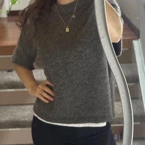 Grå stickad tröja från Gina Tricot - Mysig grå stickad tröja från Gina Tricot i premiumkvalitet. Tröjan har korta ärmar och en rund halsringning.En stilren och bekväm baströja, den är i nyskick och använts ett fåtal gånger 💕