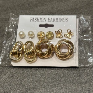 Set med guldörhängen - Säljer ett set med flera par guldörhängen. Inkluderar olika stilar som tvinnade ringar, pärlor och små blommor. Perfekt för att mixa och matcha till olika tillfällen.