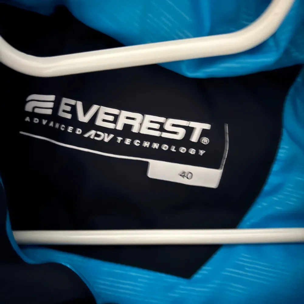 Säljer en mörkblå dunjacka från Everest med dragkedja och huva. Jackan har en stilren design med långa ärmar och är perfekt för kalla dagar. Den är utrustad med praktiska fickor med dragkedjor.. Takit.
