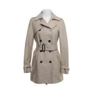 Trench Coat - Hej!! Säljer denna superfina beiga trench coaten då den helt enkelt inte kommer till användning. Den är köpt på Zara för ca 1 år sedan men har knappast blivit använd, därav inga defekter. Trench coaten finns inte kvar att köpa på Zara vad jag vet. Den går både att klä upp och klä ner och är formar sig fint efter ens kroppstyp. Om du skulle ha några frågor är det bara att höra av dig! Annars går det bra att köpa genom ”köp nu”, priset går även att diskutera.