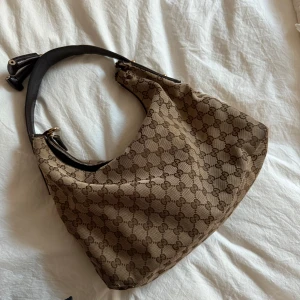 Gucci väska - Säljer min älskade Gucci Hobo väska då jag köpt en ny! Självklart äkta och finns serienummer som bekräftar detta. Obs Ena bandet är avklippt då jag tyckte det blev för mycket med det. Finns även  slitage i tyget. Säljer den billigt just pga anmärkningarna. 💕💕💕 vid snabb affär kan pris diskuteras 