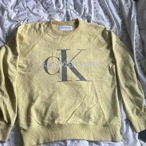  Sweatshirt från Calvin Klein - En snygg gul sweatshirt från Calvin Klein Jeans med det ikoniska CK-logotypen tryckt på framsidan. Tröjan har långa ärmar och en rund halsringning. Perfekt för en avslappnad stil. Skriv vid funderingar 💫✨