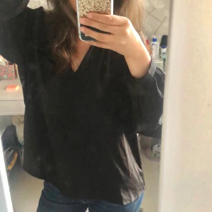 Blus - Säljer en snygg svart blus från Aware (köpt på Vero Moda) i storlek XS. Blusen har en v-ringad hals och långa ärmar. Perfekt för både vardag och fest! Den är i bra skick och väldigt bekväm att ha på sig. Passar bra till jeans eller kjol. 🌟