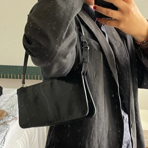 Svart axelväska i syntetmaterial - Säljer en snygg svart axelväska i läder från St. Sulpice.