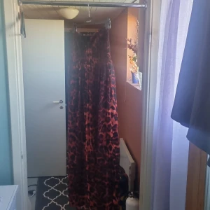 Röd och svart långklänning från Lindex - Säljer en superfin röd och svart långklänning från Lindex. Klänningen har ett coolt leopardmönster och är perfekt för festliga tillfällen. Den har en knytning vid halsen och är i ett lätt och luftigt material, vilket gör den bekväm att bära. Passar perfekt till höst och vinterfester! 🖤❤️