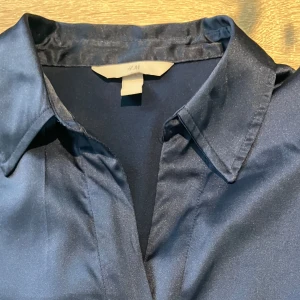 Glansig blus - Glansig blus i marinblå från HM storlek M. Fint skick 